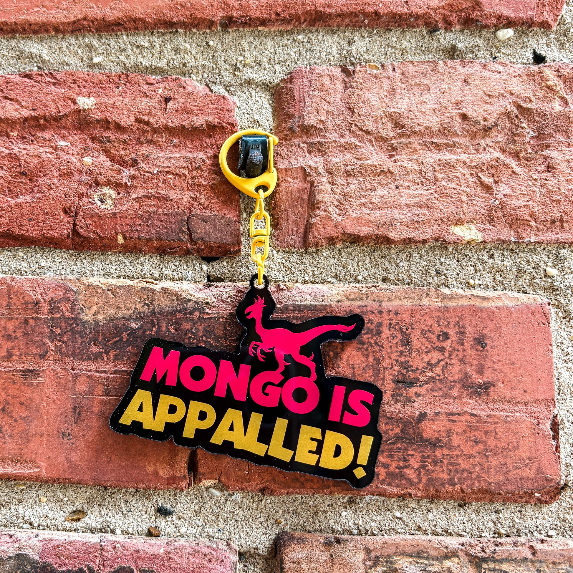 Keychain with 'Mongo is Appalled!' text on a brick wall background