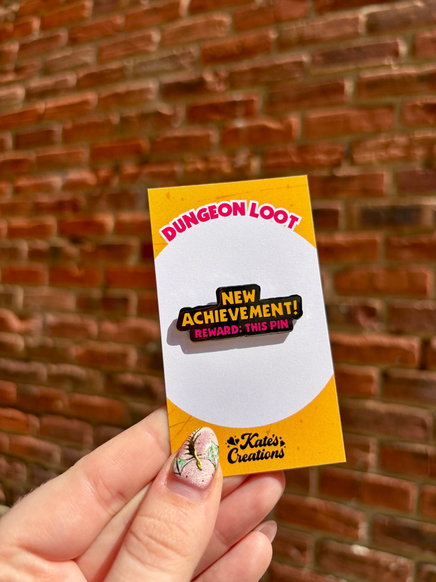 Card with 'Dungeon Loot' and 'New Achievement!' text held against a brick wall.
